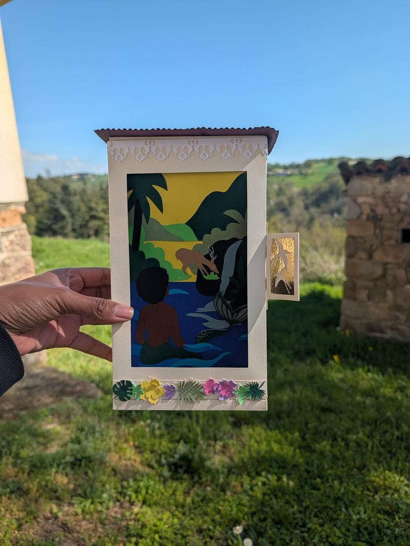 Le Théâtre de Papier tenu ouvert à la main, scène illuminée visible